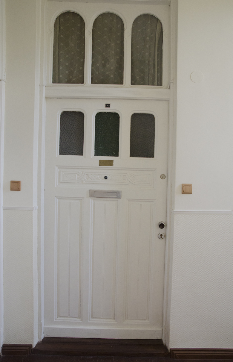 białe odmalowane drzwi w kamienicy